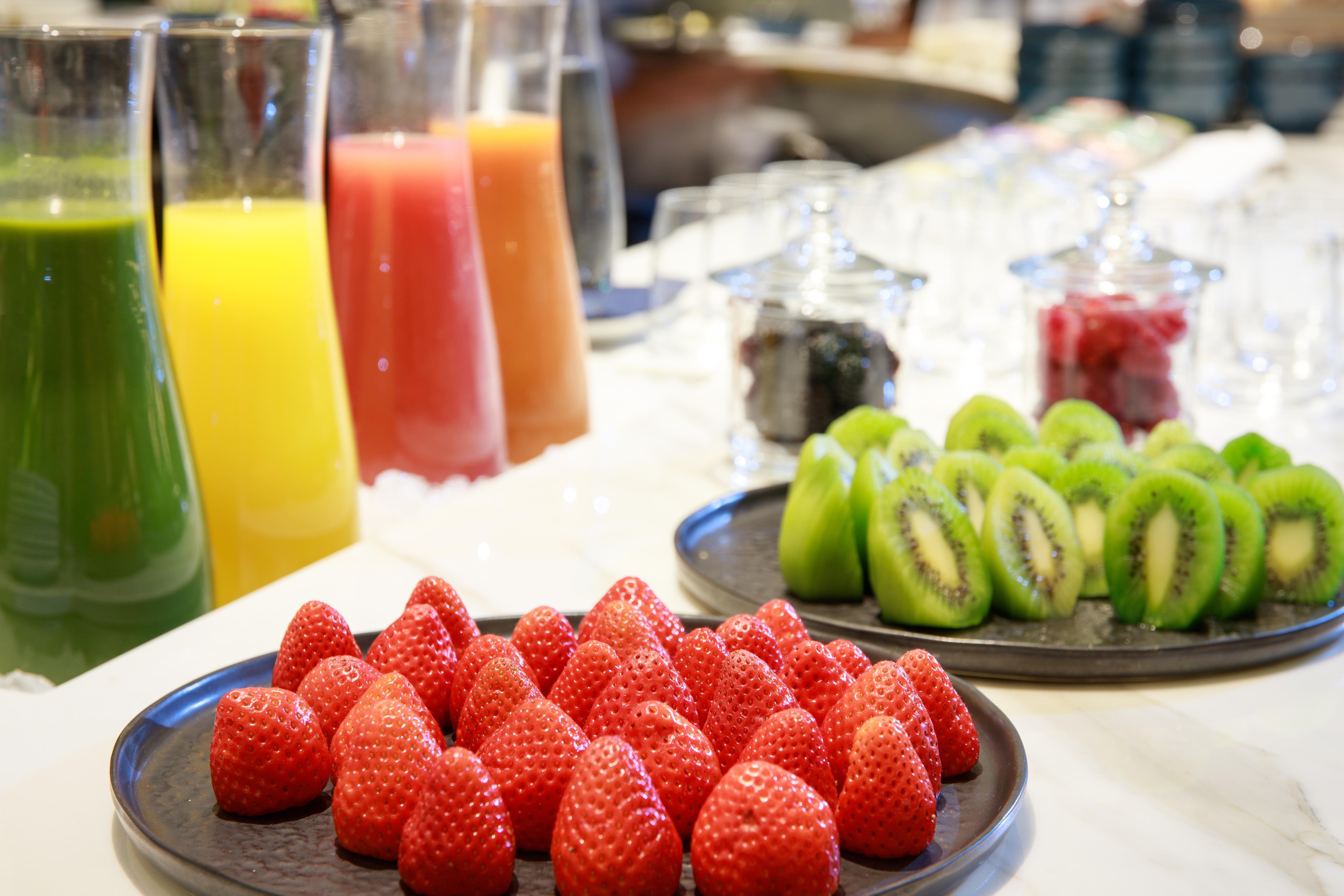 ホテル ソフィア バルセロナ イン ザ アンバウンド コレクション バイ ハイアット エクステリア 写真 The photo displays a vibrant assortment of fresh fruits and juices. In the foreground, there is a plate of bright red strawberries neatly arranged. Behind the strawberries, there are several tall glasses filled with various juices, including orange, 