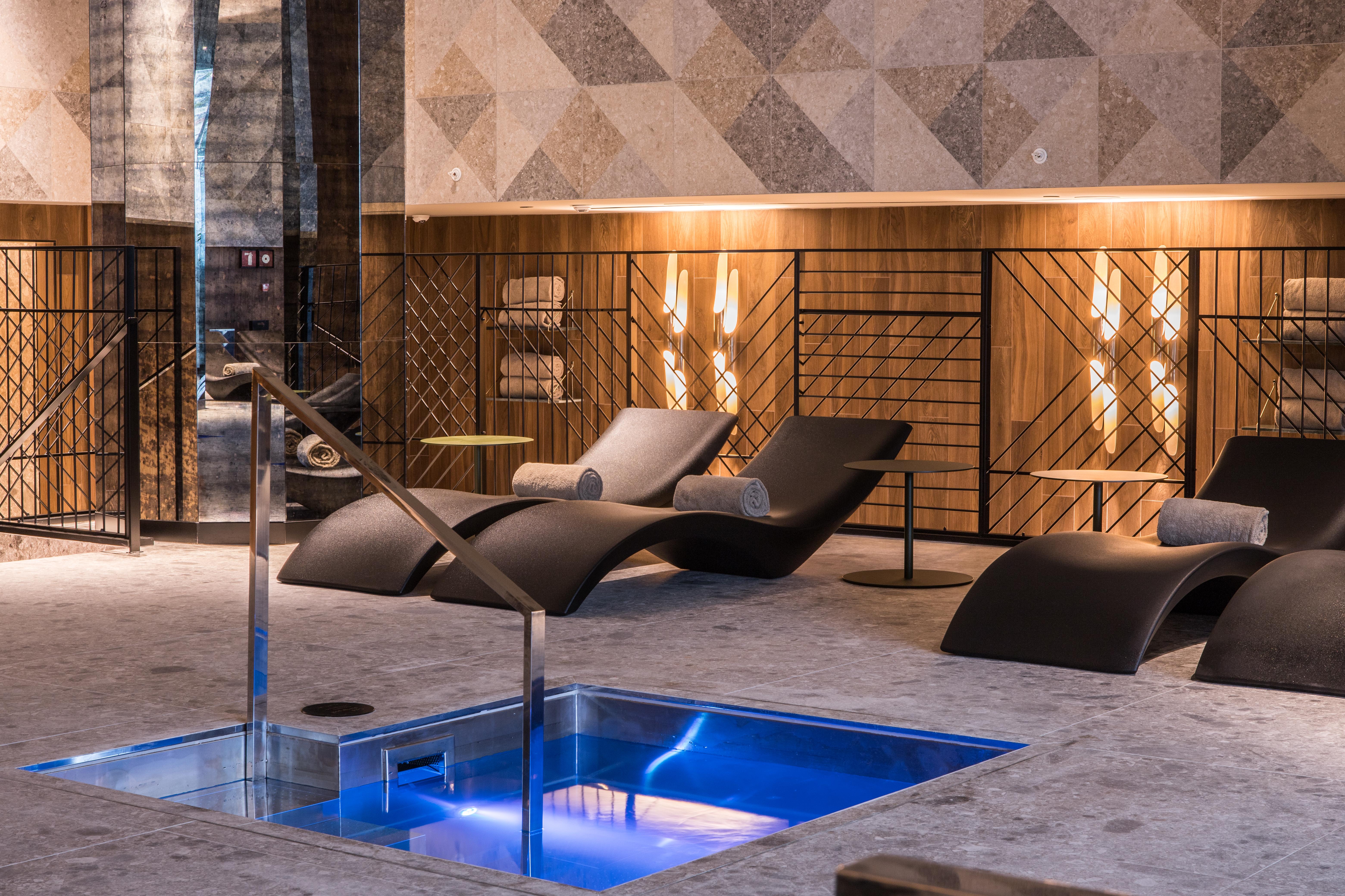 ホテル ソフィア バルセロナ イン ザ アンバウンド コレクション バイ ハイアット エクステリア 写真 The photo shows a modern spa or relaxation area. In the foreground, there is a small rectangular pool of water with a sleek metal railing. Surrounding the pool are comfortable lounge chairs, designed for relaxation, likely positioned for users to unw